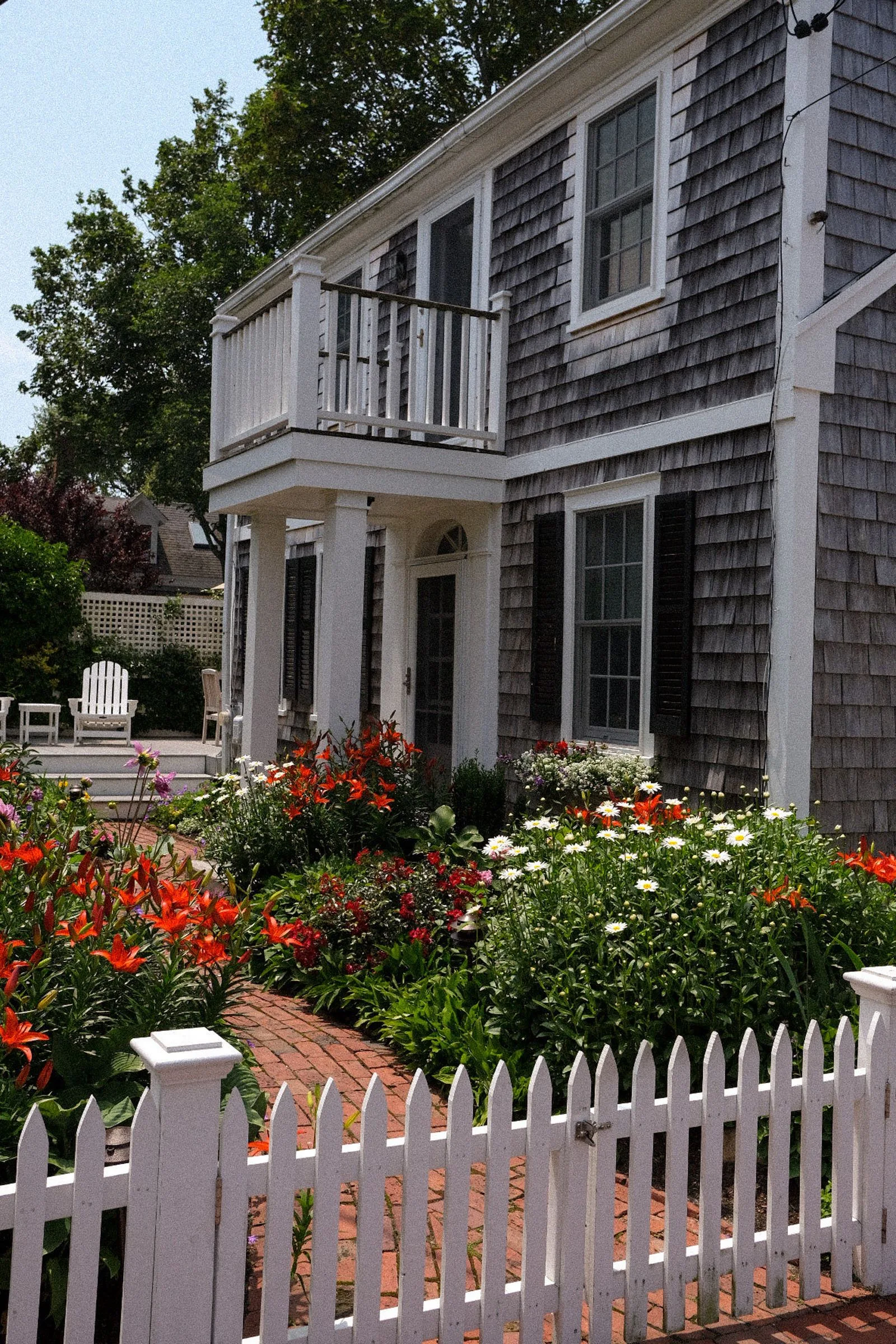 A shingled home surrounded by flowers