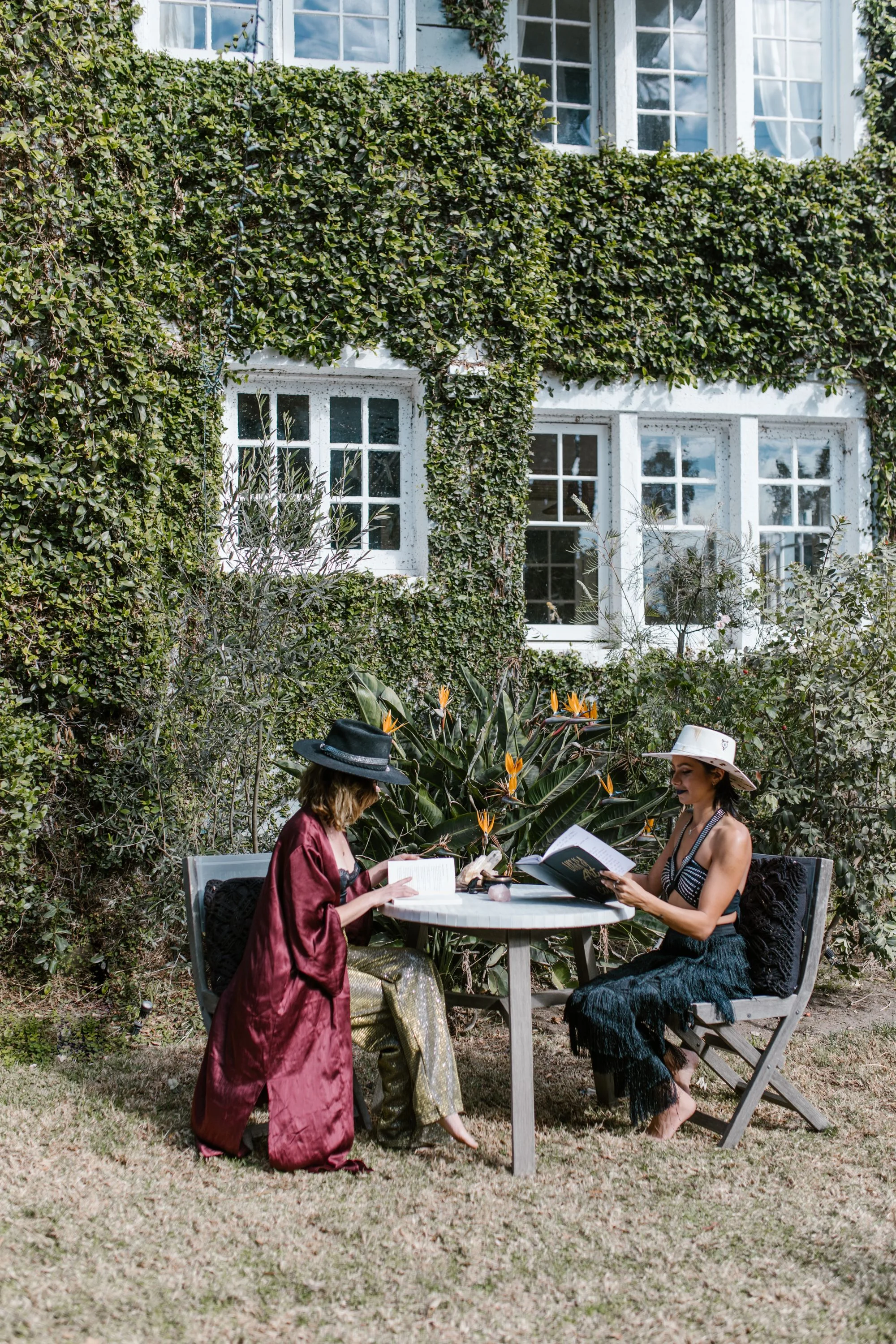 Friends reading in a leafy garden beside their home